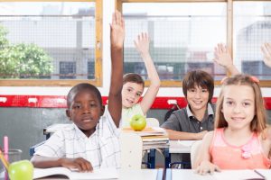 kids in the classroom raising hands